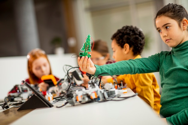 Grupo de niños felices que programan juguetes eléctricos y robots en el aula de robótica