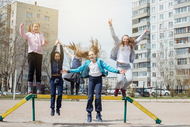 Un grupo de niños juega y se divierte en el patio de recreo cerca de la escuela después de la escuela. El concepto de ocio infantil, estilo de vida saludable.