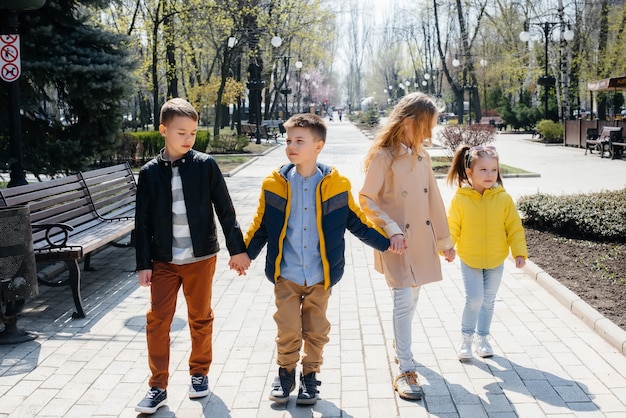 Un grupo de niños juegan juntos y caminan por el parque tomados de la mano. Amigos, niños.