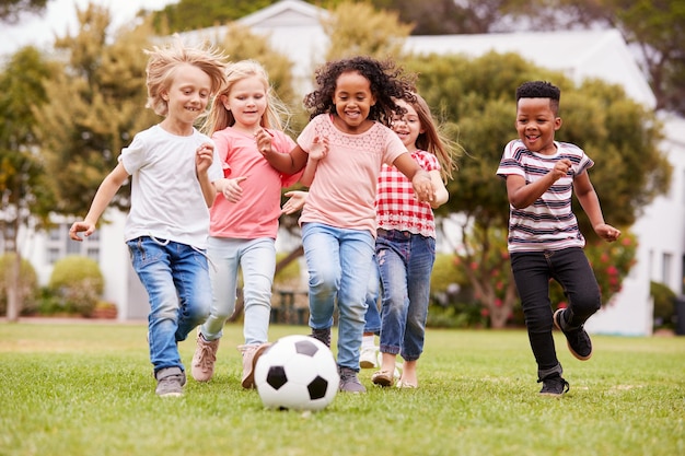 Grupo de niños jugando al fútbol con amigos en el parque