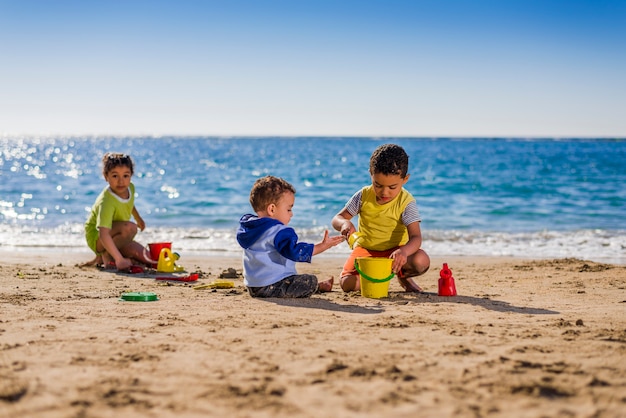 Grupo de niños jugando con juguetes de playa bajo la luz del sol