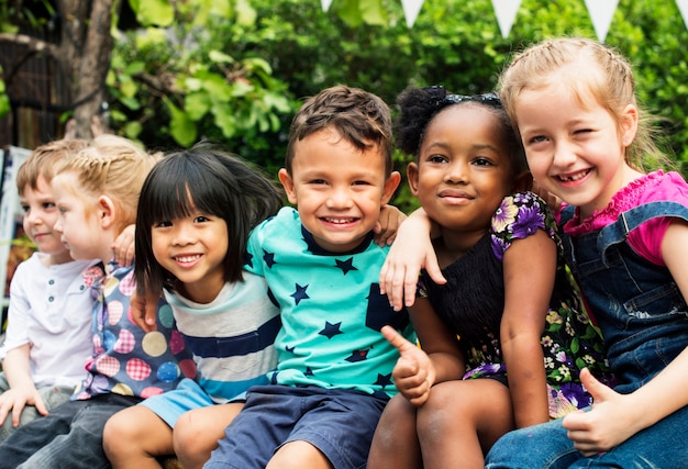 Grupo de niños de kindergarten amigos brazo alrededor sentado y sonriendo divertido