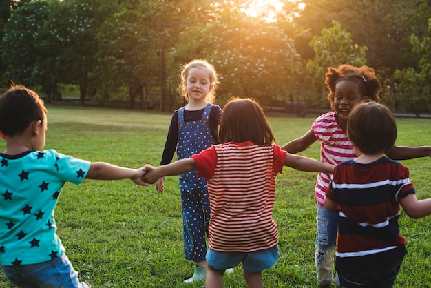 Grupo de niños de kindergarten amigos tomados de la mano jugando en el parque