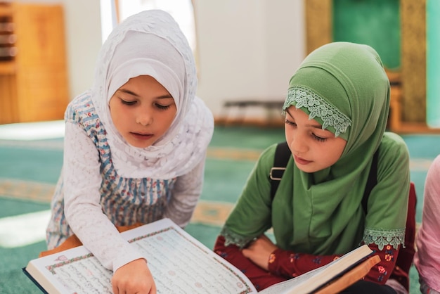 Un grupo de niños lee el Corán en la mezquita Niñas musulmanas con hiyab aprendiendo la religión islámica