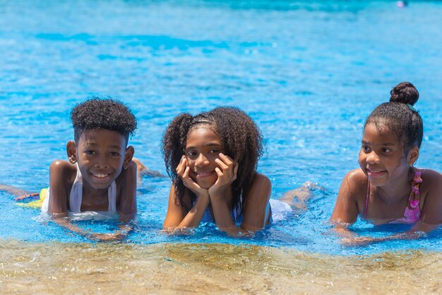 Grupo de niños negros felices jugando al aire libre en el parque de la piscina de agua en la temporada de verano