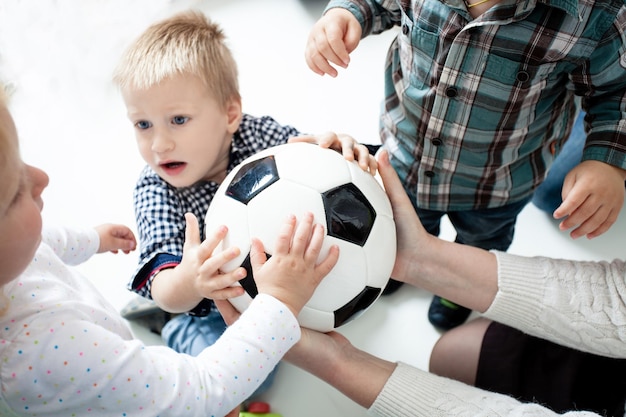 El grupo de niños pequeños se pelean por una pelota. Niños histéricos, porque un niño interceptó la pelota de otros. El concepto de niños a los que se les enseña a compartir entre ellos