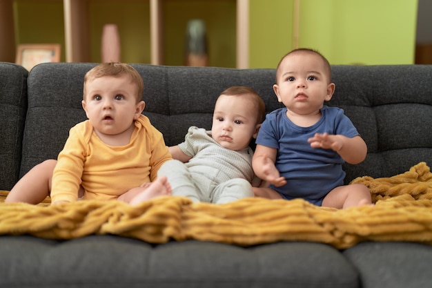 Grupo de niños pequeños sentados en un sofá en casa