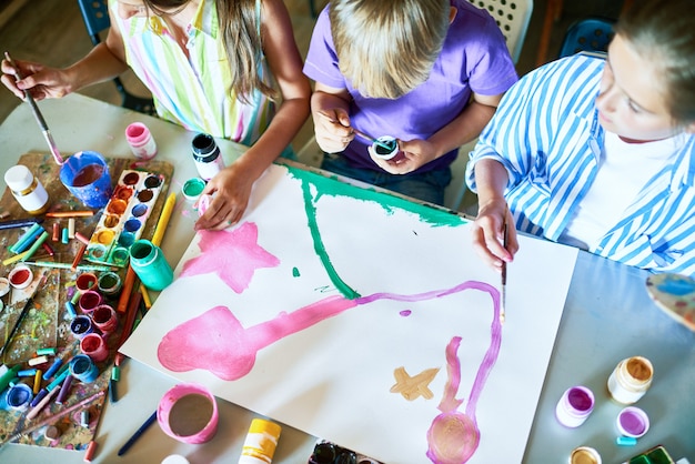 Grupo de niños pintando cuadro juntos en clase de arte