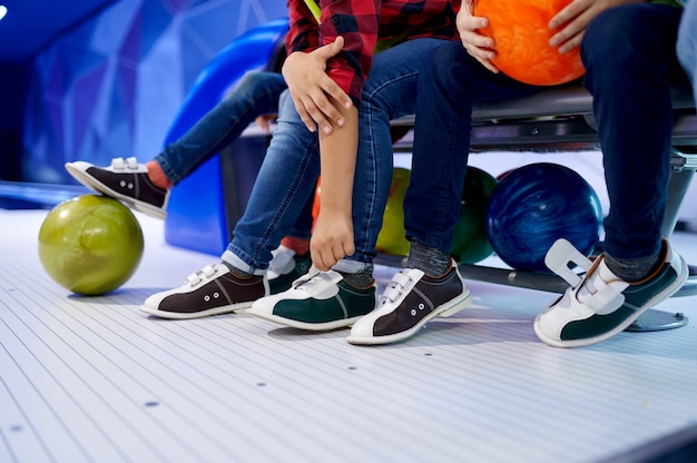 Grupo de niños se ponen zapatos de bolos en un banco