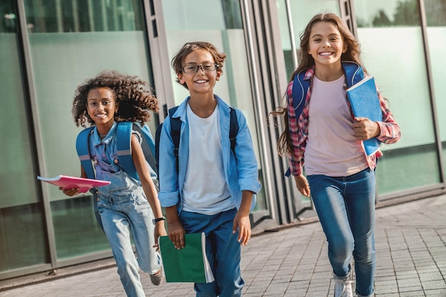 Grupo de niños de primaria saliendo corriendo de la escuela