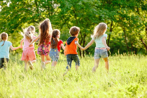 Un grupo de niños que juegan y que corren en el parque en un gozon verde.