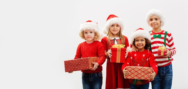Un grupo de niños con regalos de Navidad en sus manos y con disfraces navideños Grupo multiétnico