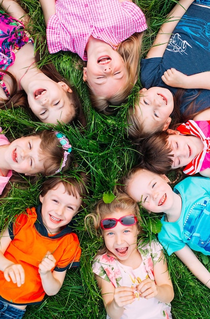 Un grupo de niños tirados en la hierba verde del parque. La interacción de los niños.