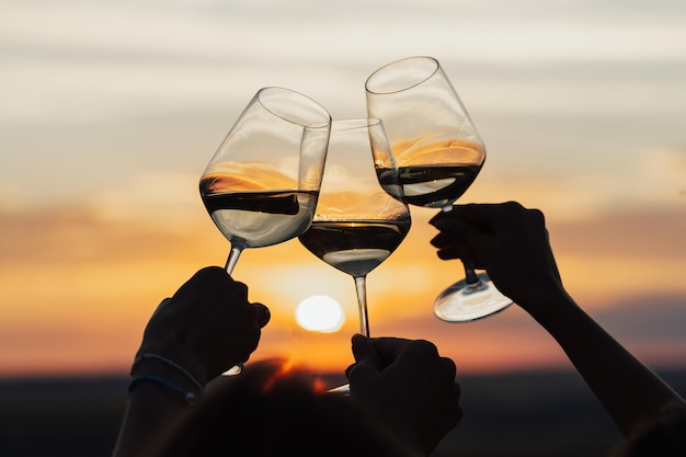 Un grupo de novias brindan con copas de vino blanco en una puesta de sol