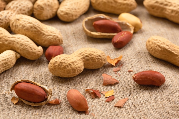 Grupo de nueces sin cáscara y sin cáscara en un acercamiento de maní de comida de burlap