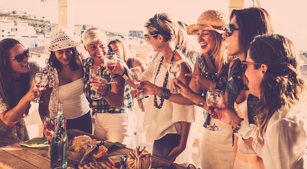 Grupo de nueve personas celebran un cumpleaños Mujeres sonrientes con mesa de madera de copa de vino tinto comida y bebida Concepto de amistad