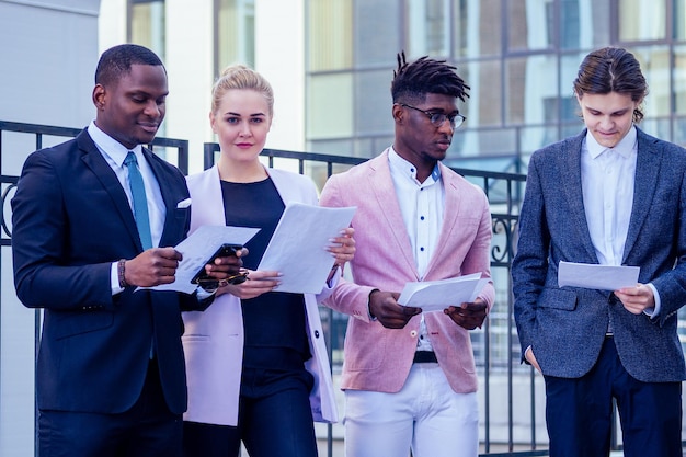 Un grupo de nueve personas multinacionales empresaria y hombre de negocios en una reunión de negocios comunicándose en el contexto de las ventanas de la oficina en la calle