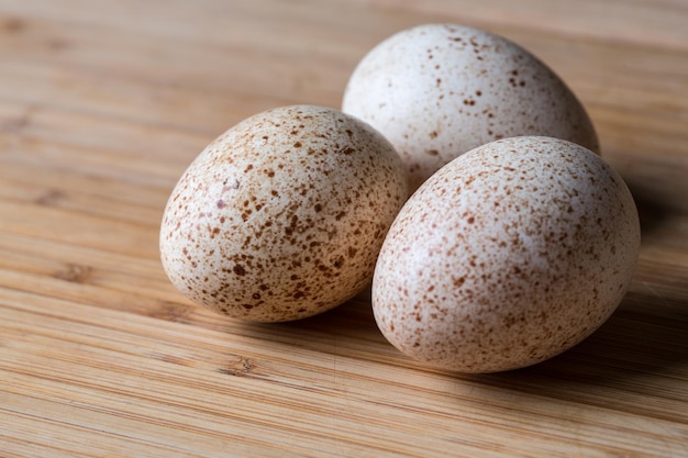 Grupo og tres huevos de pavo frescos en una tabla de bambú