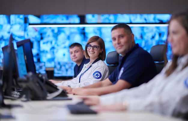 Grupo de operadores de centros de datos de seguridad que trabajan en una sala de monitoreo de CCTV mirando varios monitores Oficiales que monitorean múltiples pantallas para actividades sospechosas Equipo que trabaja en el sistema Contr