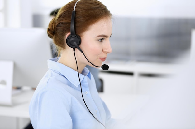 Grupo de operadores en el trabajo Centro de llamadas Centrarse en la mujer recepcionista en auriculares en servicio al cliente
