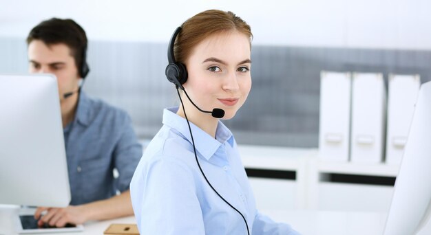 Grupo de operadores en el trabajo Centro de llamadas Centrarse en la mujer recepcionista en auriculares en servicio al cliente