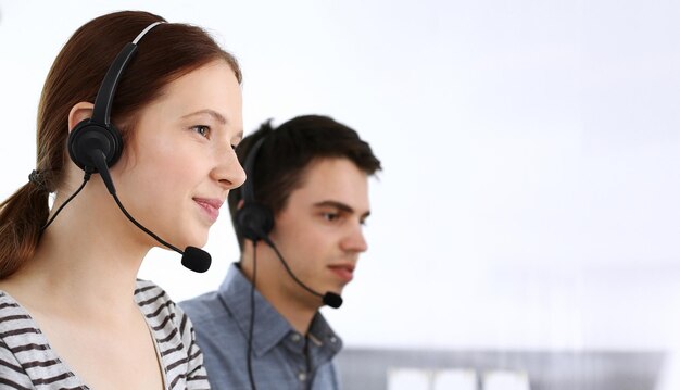 Grupo de operadores en el trabajo Centro de llamadas Centrarse en la mujer recepcionista en auriculares en servicio al cliente