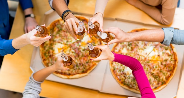 Grupo de oung personas comiendo pizza y beber sidra en la moderna vista interior desde arriba