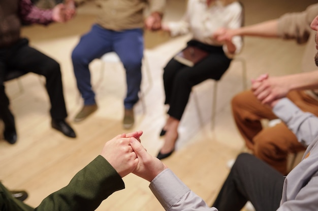 Grupo de pacientes de curso psicológico tomados de las manos durante la sesión