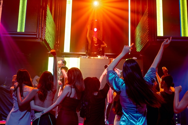 Grupo de personas bailan en la discoteca al ritmo de la música de DJ en el escenario