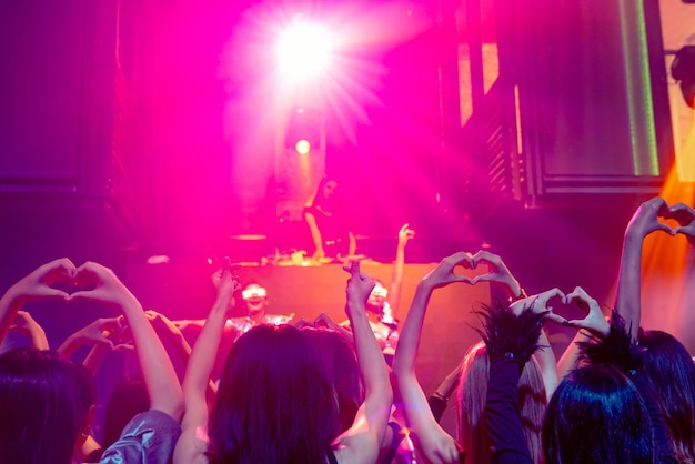 Grupo de personas bailan en la discoteca al ritmo de la música de DJ en el escenario