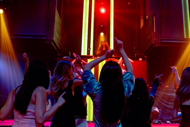 Grupo de personas bailan en la discoteca al ritmo de la música de DJ en el escenario
