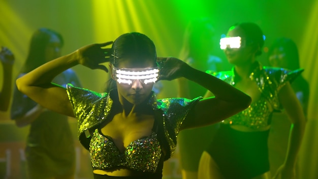 Grupo de personas bailan en la discoteca al ritmo de la música de DJ en el escenario