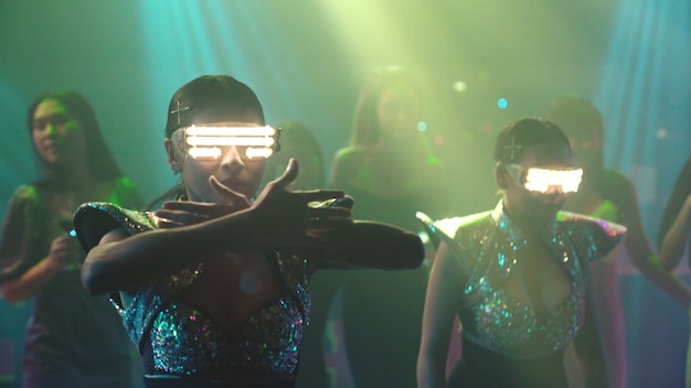 Grupo de personas bailan en la discoteca al ritmo de la música de DJ en el escenario