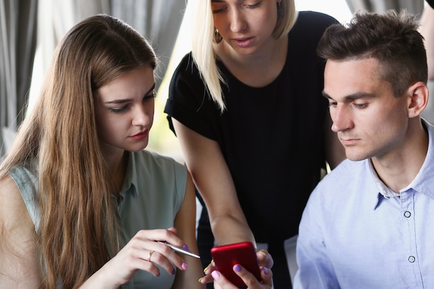 Un grupo de personas en un café mirando la aplicación para teléfonos inteligentes