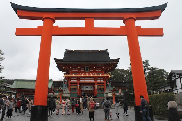 Un grupo de personas caminan alrededor de un santuario con un templo japonés en el fondo