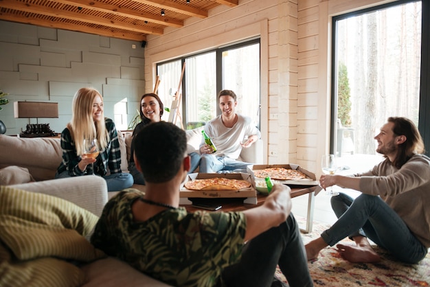 Grupo de personas comiendo pizza y relajarse en la sala de estar