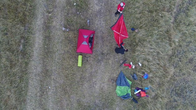 Grupo de personas disfrutando de una tienda de campaña en las montañas (vista aérea, coche no reconocible)