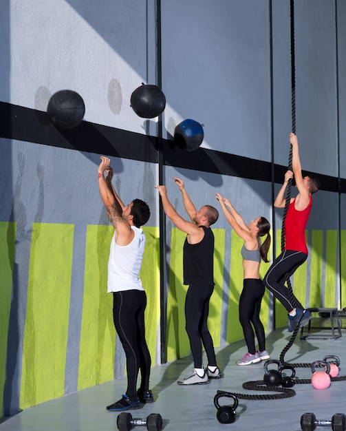 Grupo de personas de entrenamiento crossfit con bolas de pared y cuerda