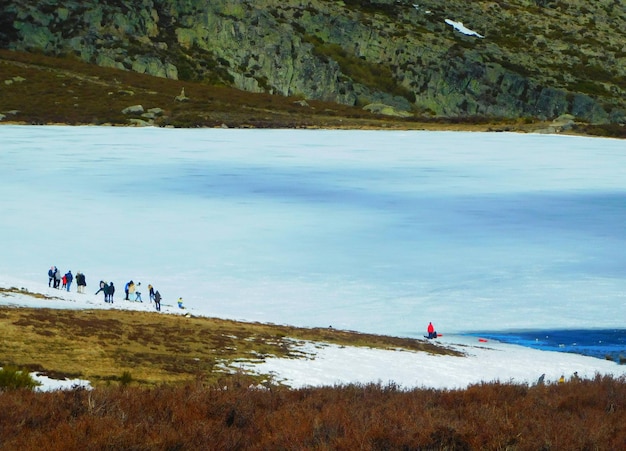 Un grupo de personas está parado en un lago congelado, uno de los cuales está cubierto de nieve.