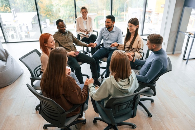 Un grupo de personas están teniendo una reunión de terapia juntos