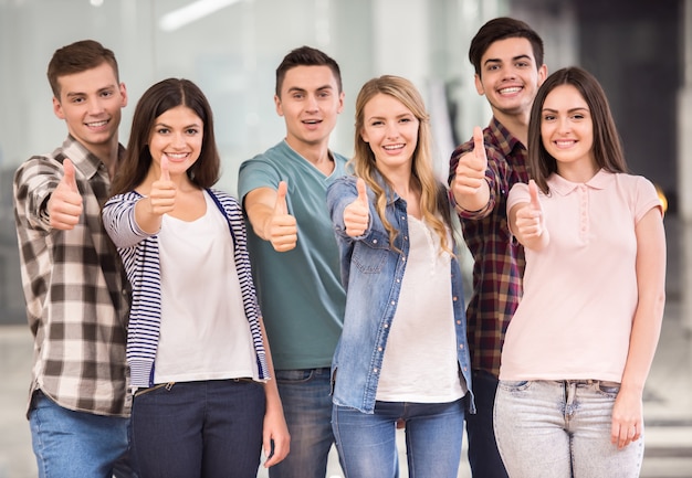 Grupo de personas felices de pie y mostrando los pulgares para arriba.