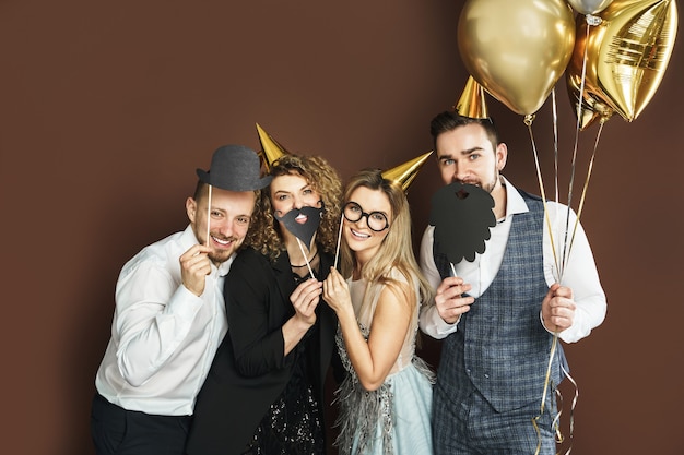 Grupo de personas felices con sombreros de fiesta con divertidos accesorios de fotomatón están celebrando vacaciones o eventos