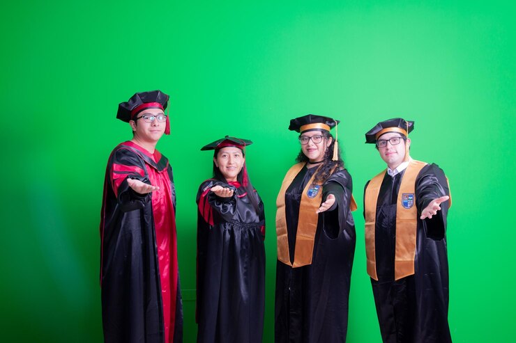 un grupo de personas con gorras de graduación de pie frente a una pantalla verde
