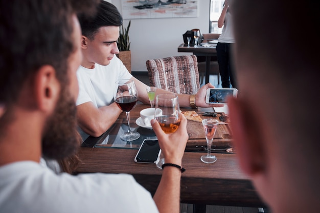 Un grupo de personas hace una foto selfie en un café. Los mejores amigos se reunieron en una mesa para comer pizza y cantar varias bebidas.