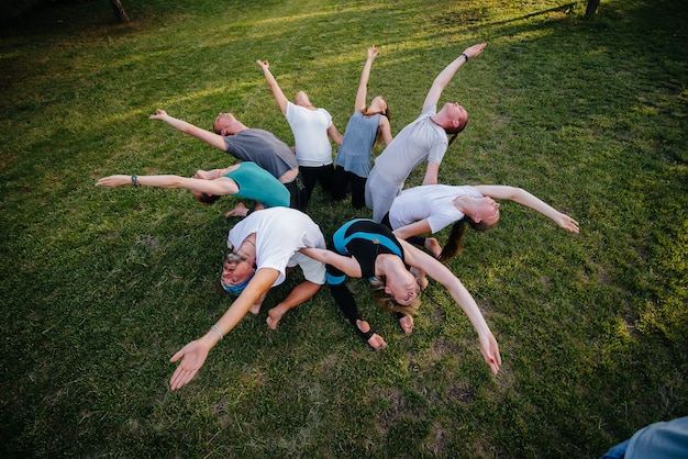 Un grupo de personas hace yoga en círculo al aire libre durante la puesta de sol. Estilo de vida saludable, meditación y bienestar.