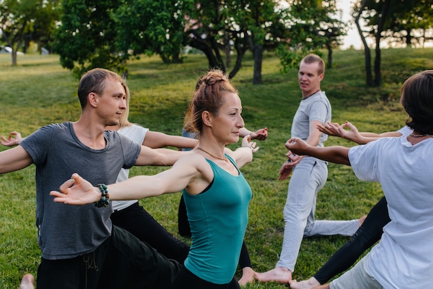 Un grupo de personas hace yoga en círculo al aire libre durante la puesta de sol. Estilo de vida saludable, meditación y bienestar.