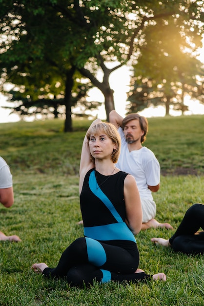 Un grupo de personas hace yoga en el parque al atardecer. Estilo de vida saludable, meditación y bienestar.