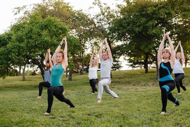 Un grupo de personas hace yoga en el parque al atardecer. Estilo de vida saludable, meditación y bienestar.