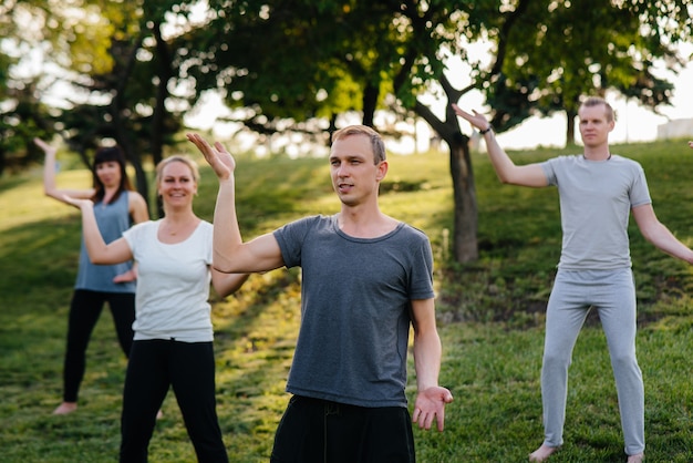 Un grupo de personas hace yoga en el parque al atardecer. Estilo de vida saludable, meditación y bienestar.