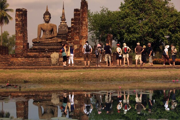 Foto grupo de personas junto a una gran estatua de buda